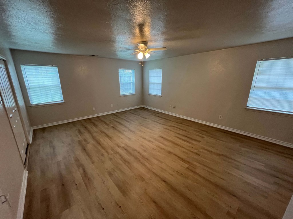 an empty living room with wood floors and a ceiling fan