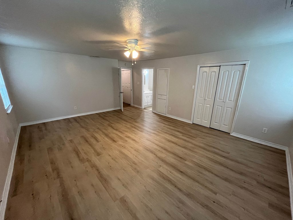 an empty living room with wooden floors and a ceiling fan