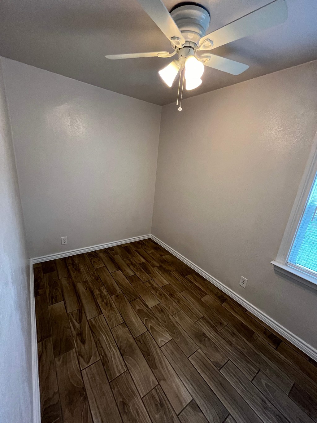 a empty bedroom with wood flooring and a ceiling fan
