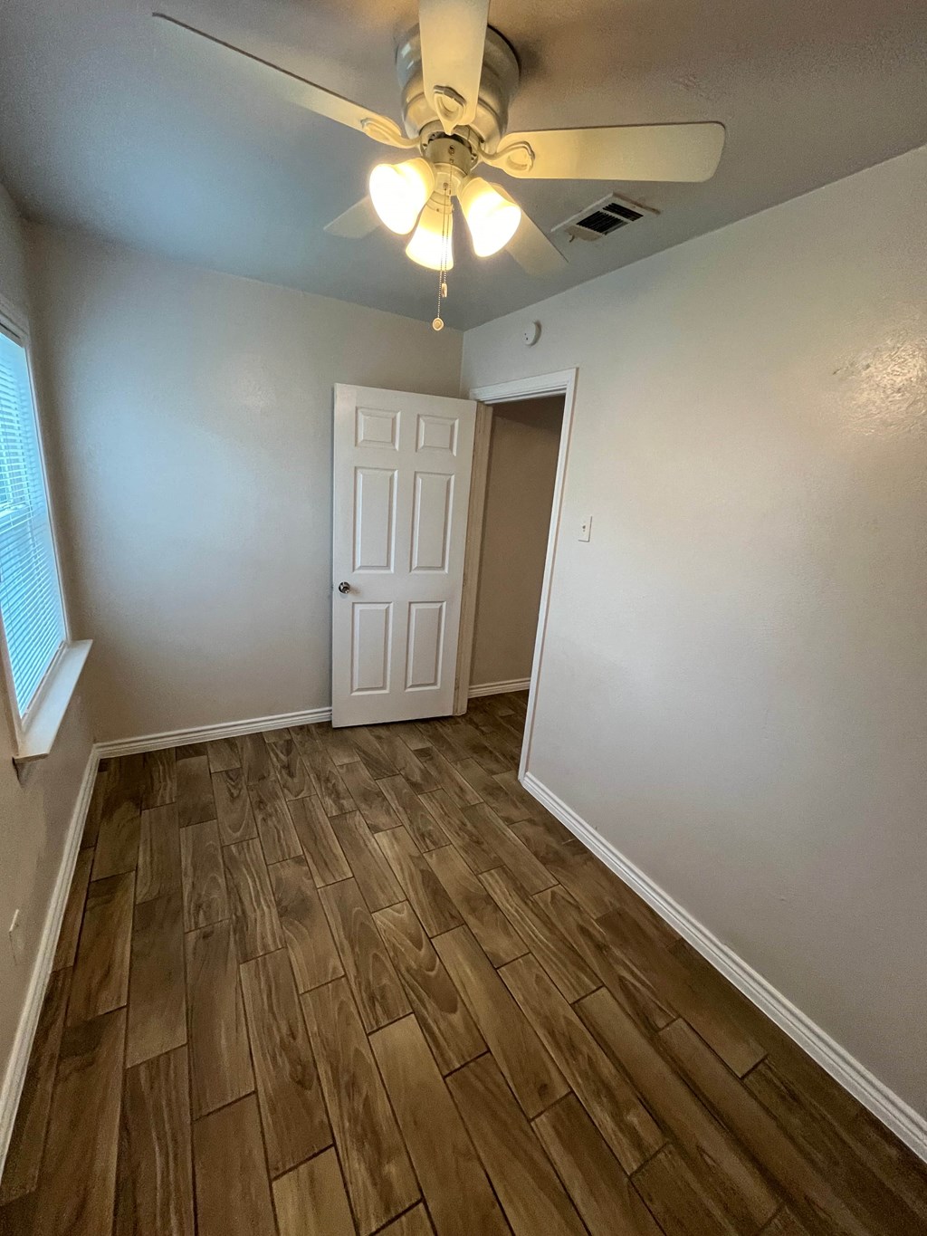 an empty living room with wood flooring and a ceiling fan