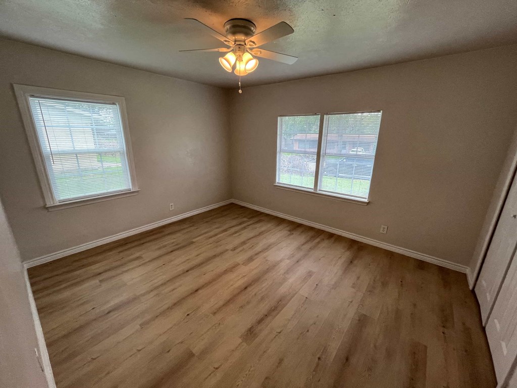 an empty bedroom with wooden floors and a ceiling fan