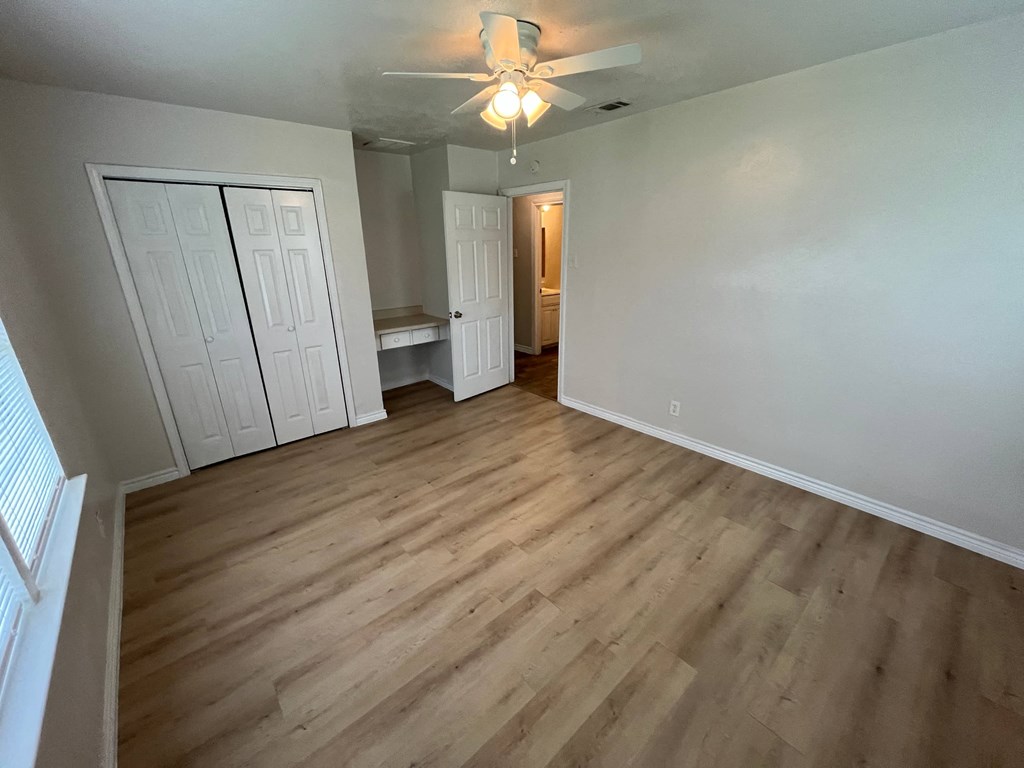 an empty living room with wood floors and a ceiling fan