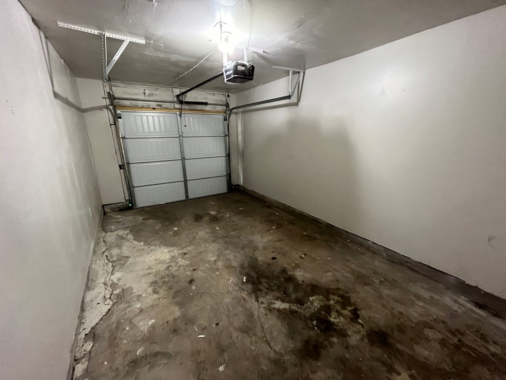 a white room with a concrete floor and a garage door