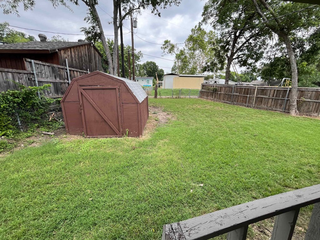 a backyard with a small shed in the grass