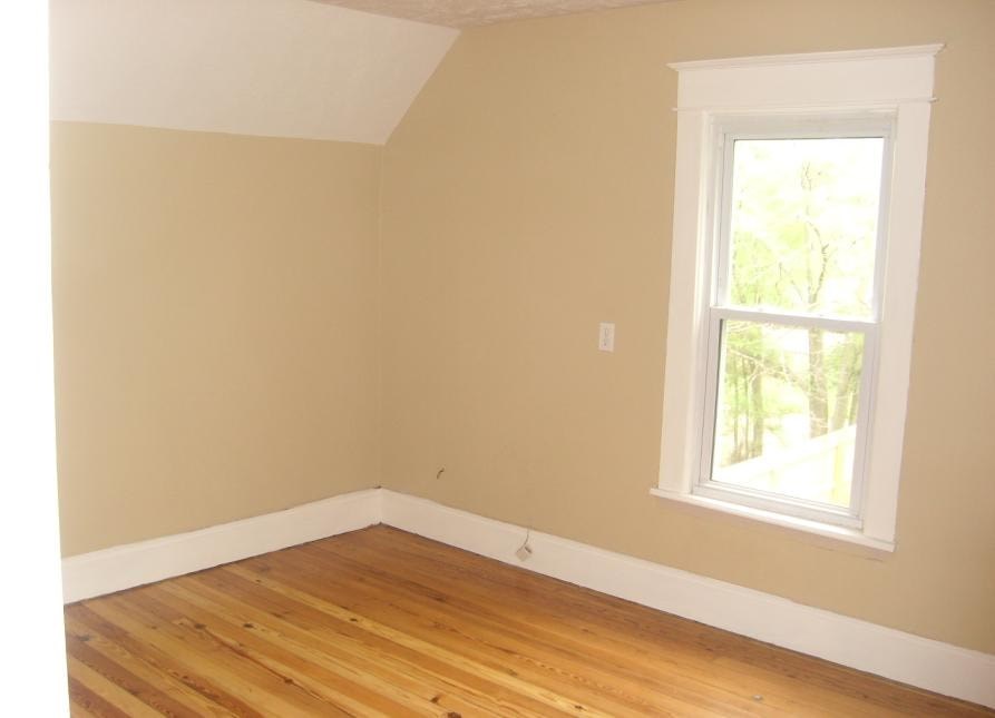A room with a window and wooden floors.