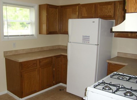 A white refrigerator in a kitchen with wooden cabinets.