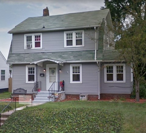 a gray house with a green roof and a yard