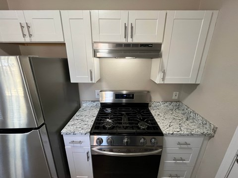 A kitchen with a stove top oven and a refrigerator.
