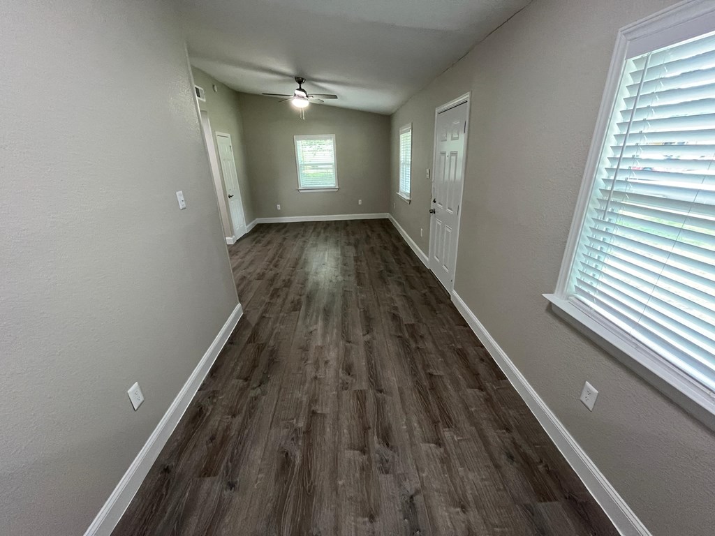 a long hallway with wood flooring and a ceiling fan