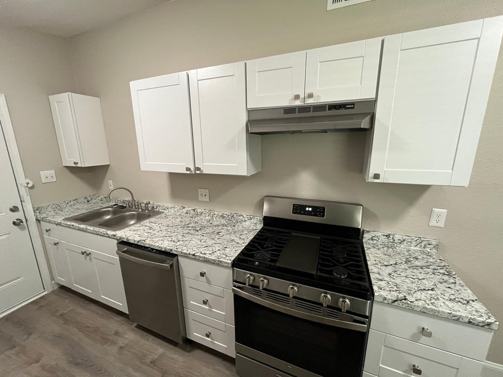a kitchen with white cabinets and granite counter tops and stainless steel appliances