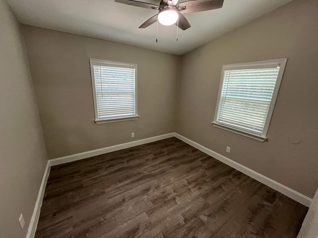 an empty bedroom with wood floors and a ceiling fan