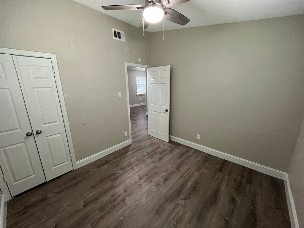 an empty living room with wood flooring and a ceiling fan