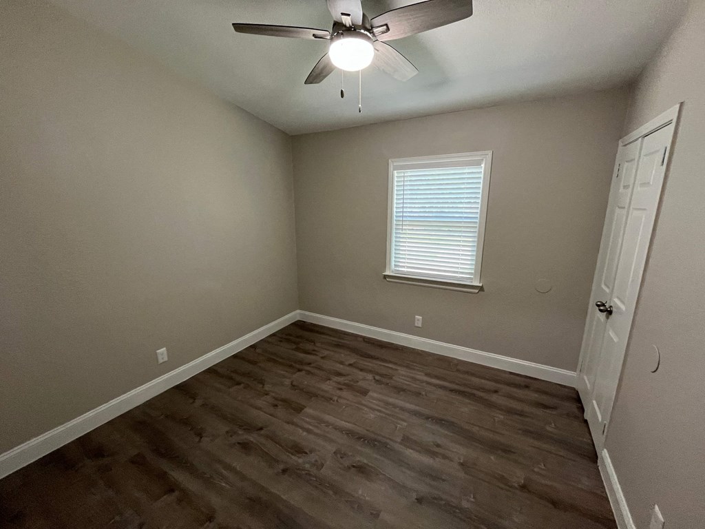 a bedroom with hardwood flooring and a ceiling fan
