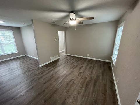 A room with a ceiling fan and wooden flooring.