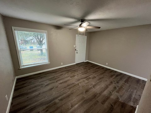 A room with a ceiling fan and a window with blinds.