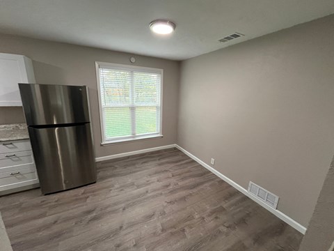 A kitchen with a stainless steel refrigerator and wooden flooring.
