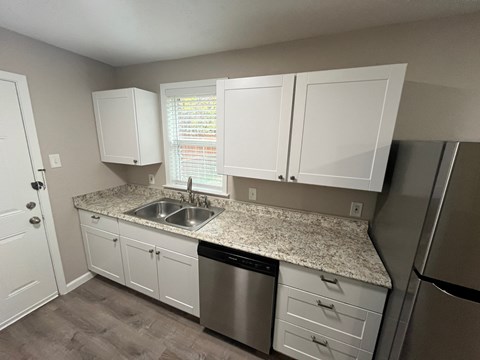 A kitchen with white cabinets and a granite countertop.