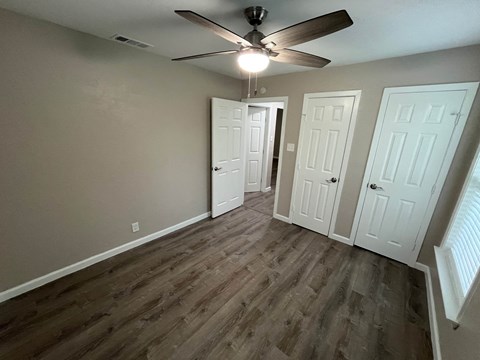 A room with a ceiling fan and three doors.