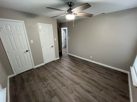 A room with a ceiling fan and wooden flooring.