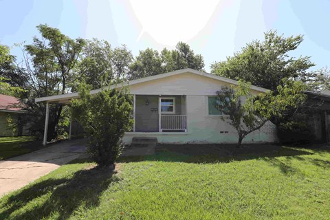 A house with a white front porch and a tree in front.