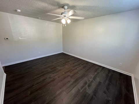 A room with a ceiling fan and wooden flooring.