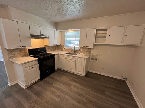 A kitchen with white cabinets and a black stove top oven.