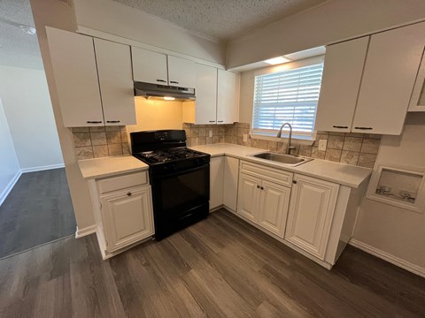 A kitchen with white cabinets and a black stove top oven.