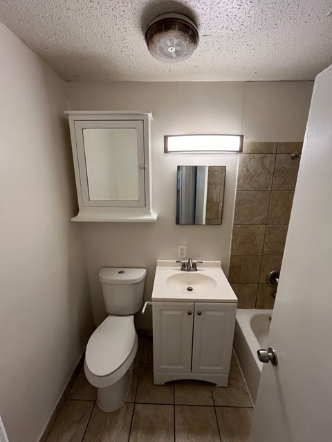 A small white bathroom with a toilet, sink and medicine cabinet.