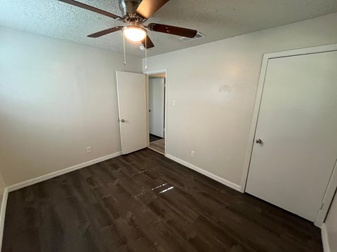 A room with a ceiling fan and wood flooring.