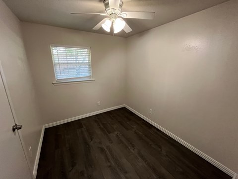 A room with a ceiling fan and a window with blinds.