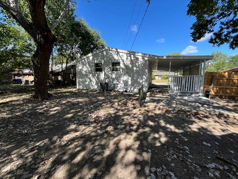 A white building with a tree in front of it.
