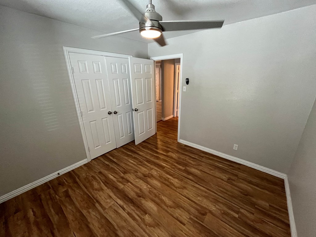 a bedroom with wood flooring and a ceiling fan
