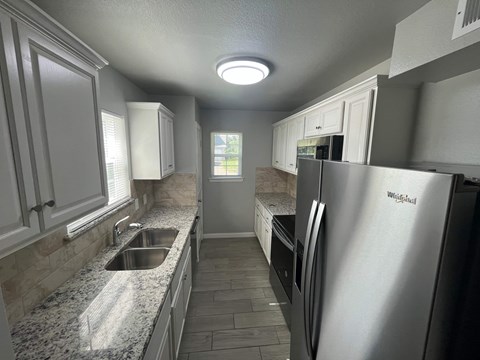 A kitchen with a stainless steel refrigerator and a sink.