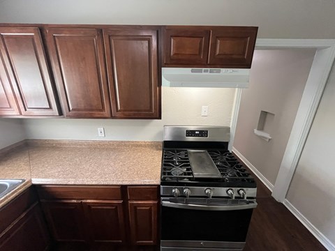 A kitchen with a stove top oven and wooden cabinets.