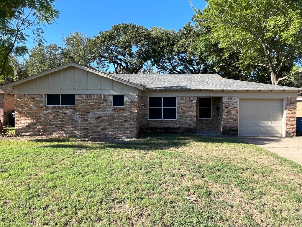 a small brick house with a lawn and trees