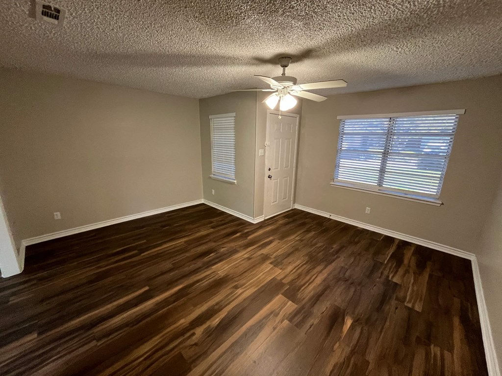 an empty living room with wooden floors and a ceiling fan