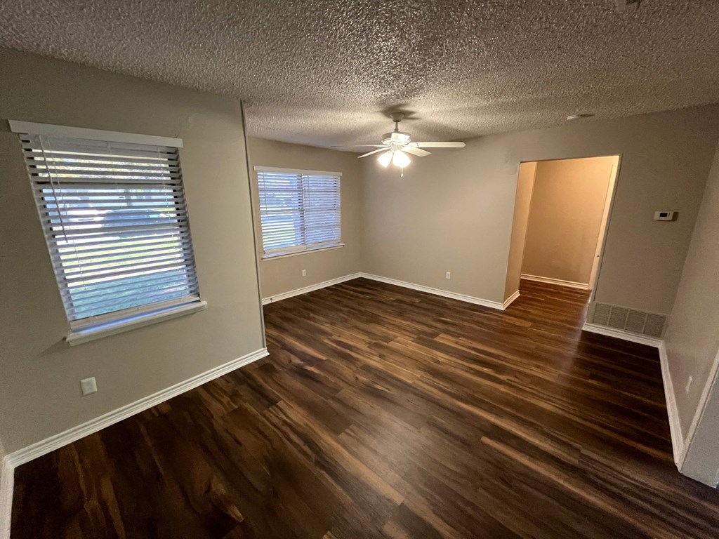 an empty living room with wooden floors and a ceiling fan