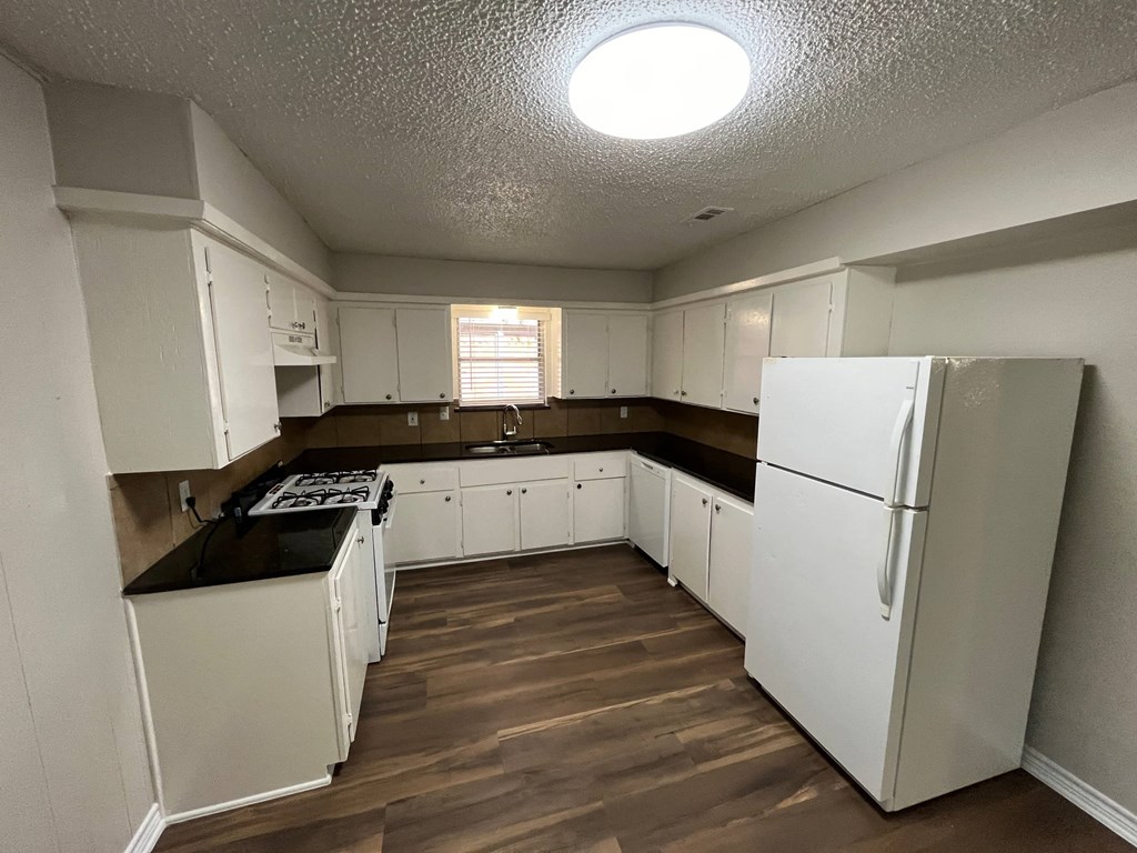 an empty kitchen with white cabinets and a refrigerator