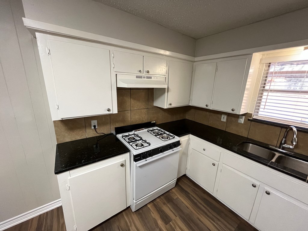 a kitchen with white cabinets and a stove and a sink