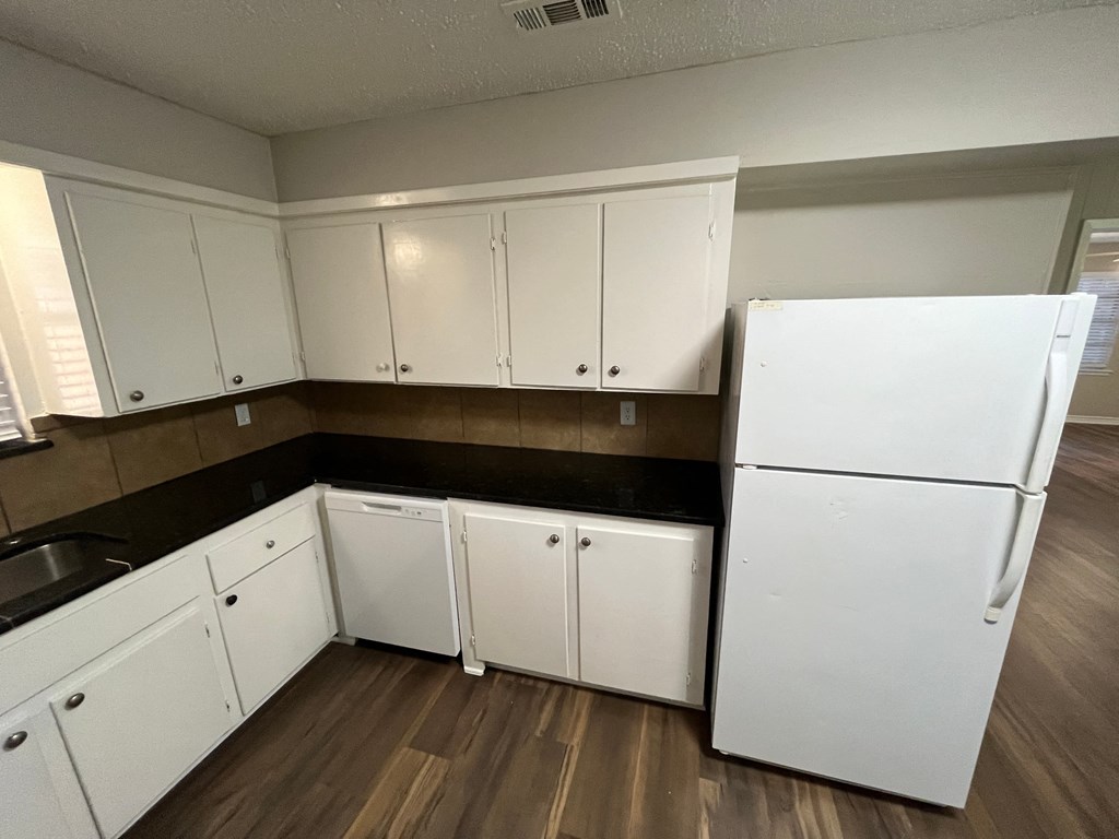 an empty kitchen with white cabinets and a refrigerator