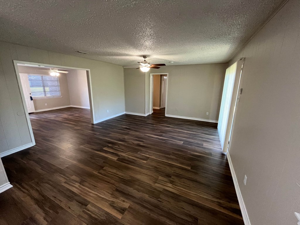 an empty living room with wooden floors and a ceiling fan