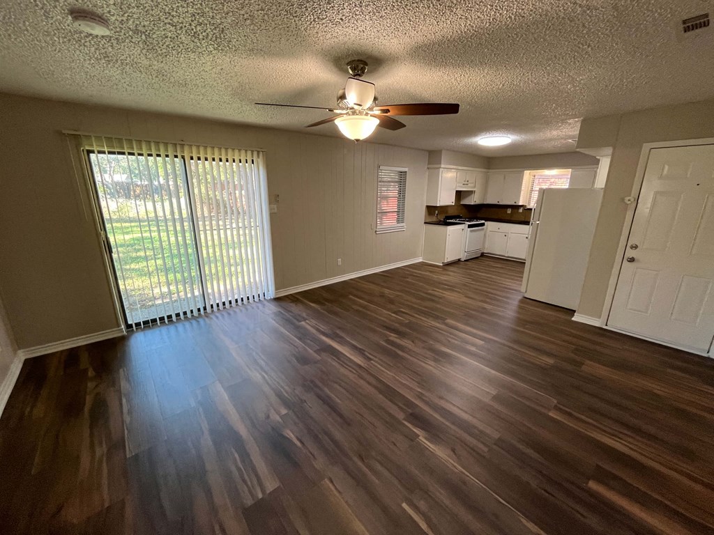 an empty living room with wood floors and a ceiling fan