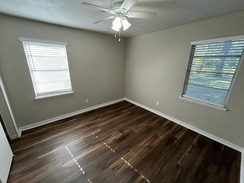 an empty living room with wooden floors and a ceiling fan