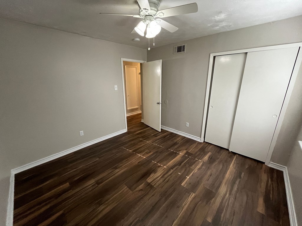an empty living room with wood flooring and a ceiling fan