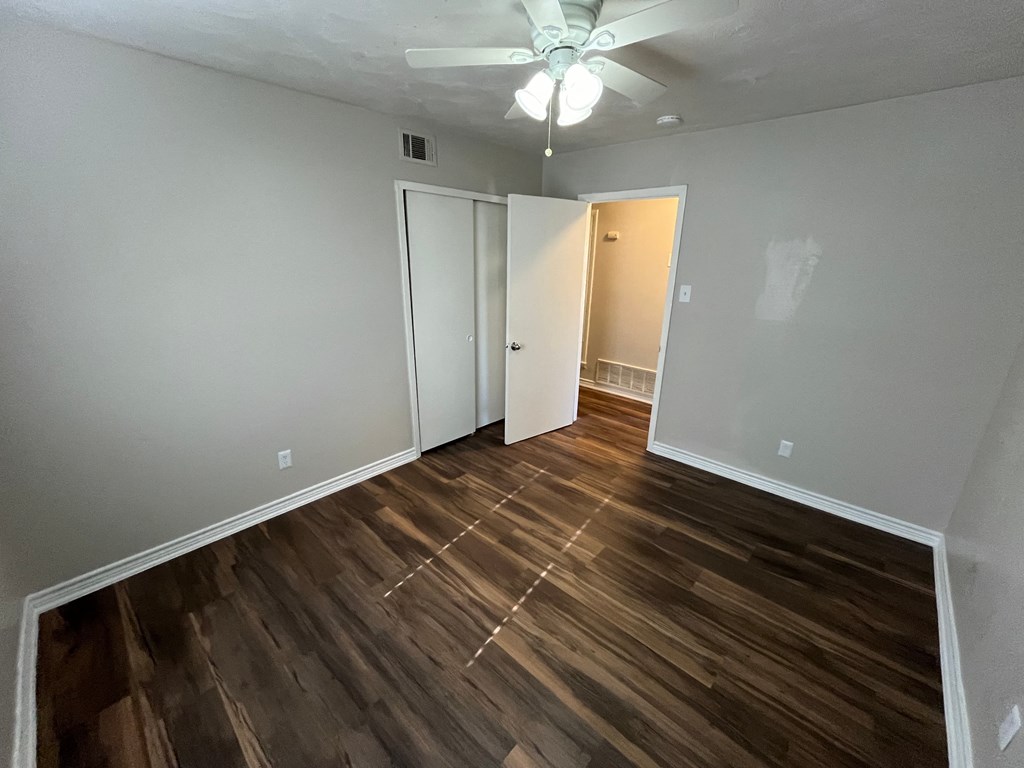 an empty living room with wooden floors and a ceiling fan
