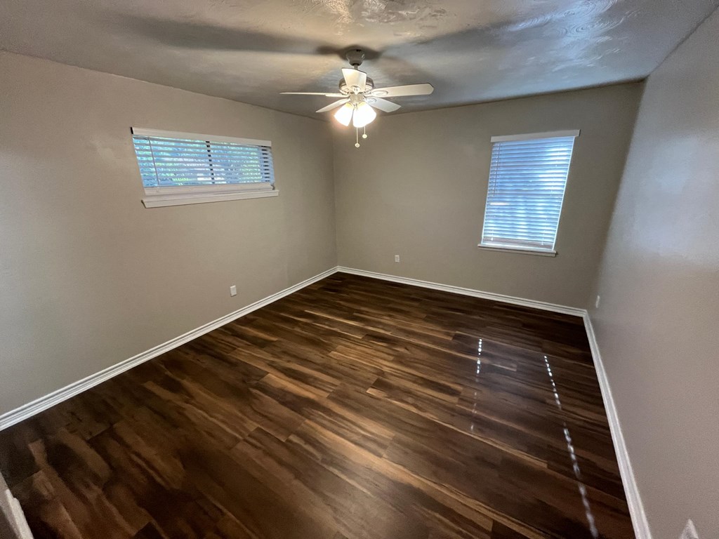an empty living room with wooden floors and a ceiling fan