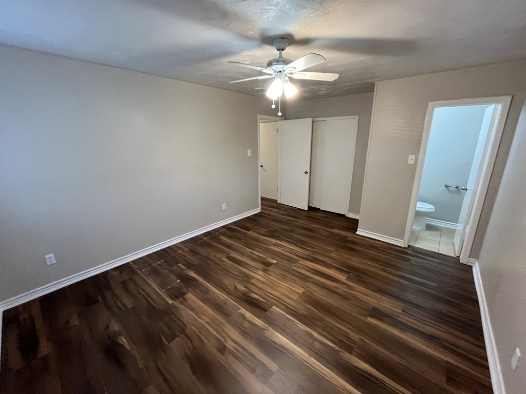 an empty living room with wooden floors and a ceiling fan