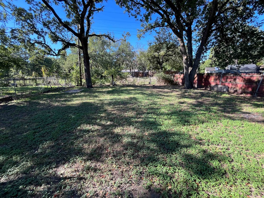 a large yard with trees and a brick wall