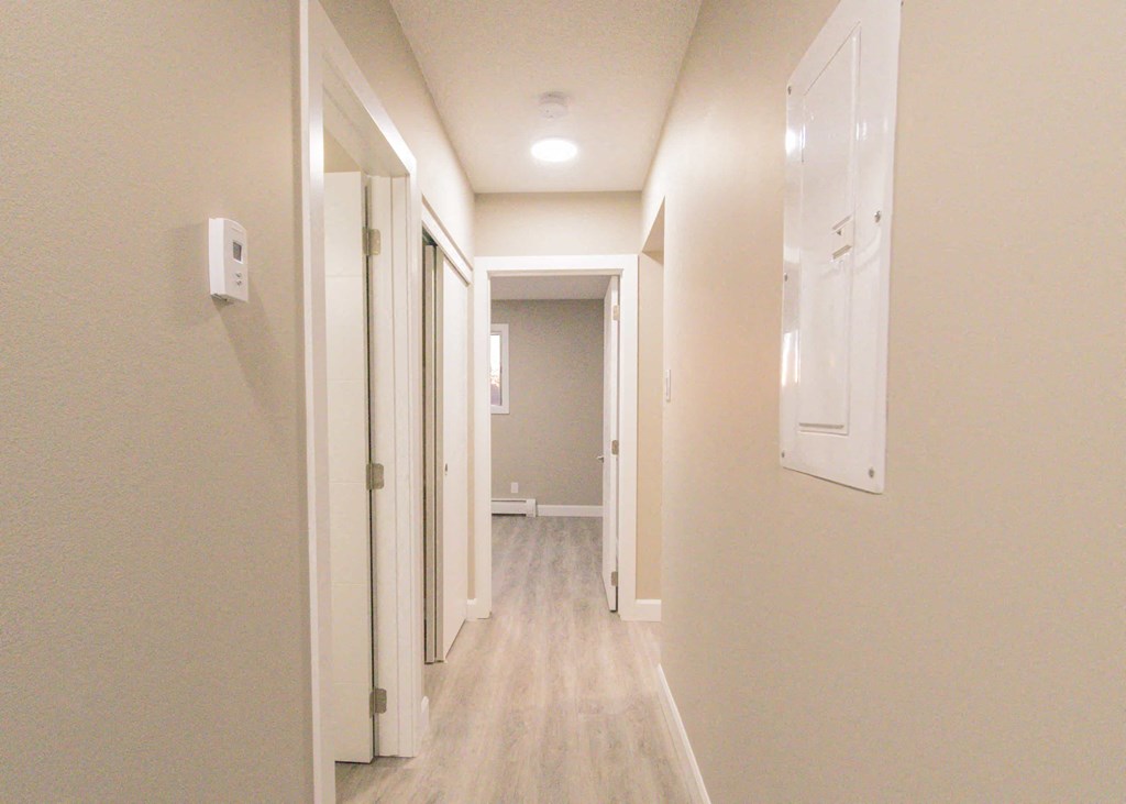 a long hallway with white doors and white walls and wood floors