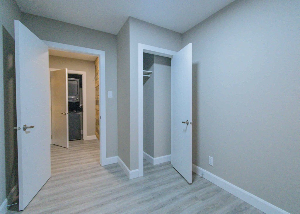 an empty room with doors to a closet and a hallway